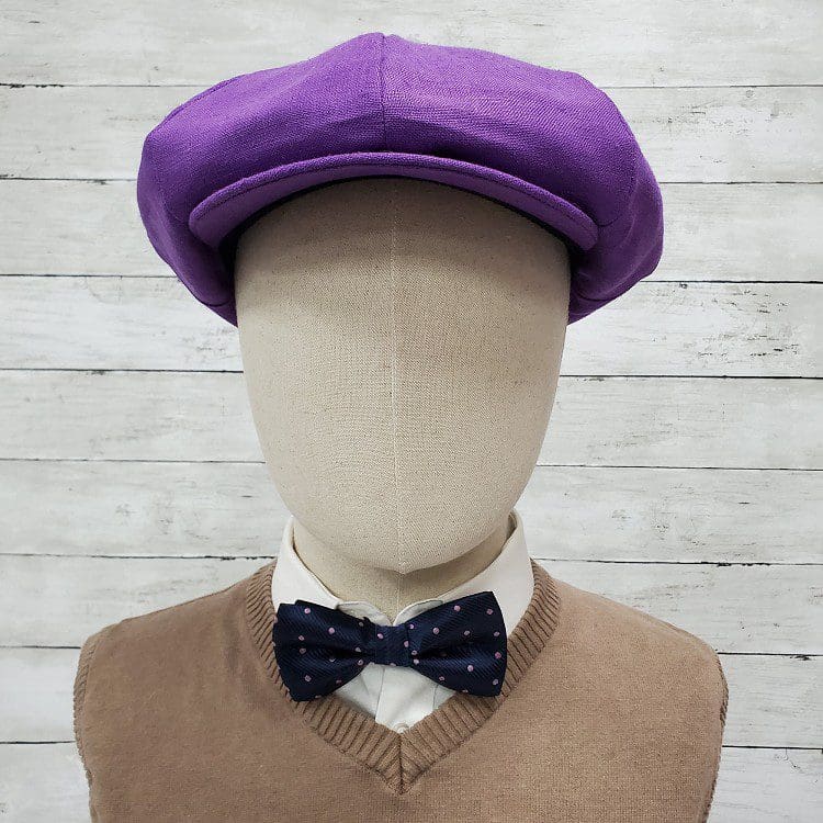 A mannequin wearing a purple hat and bow tie.