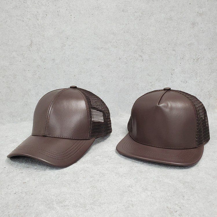 A brown leather hat is next to another hat.